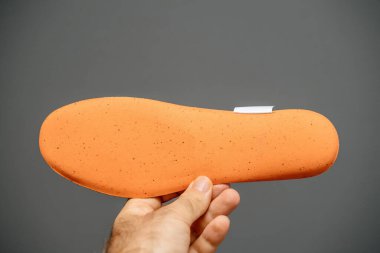 Erkek el, yeni koşu ayakkabısını turuncu renkte tutuyor.