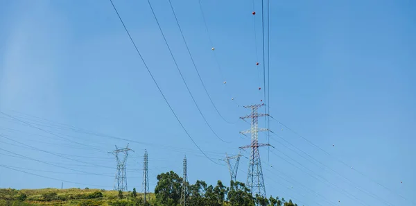 Duże słupy energii elektrycznej na wzgórzach austriackich ze spokojnym błękitnym niebem w tle — Zdjęcie stockowe