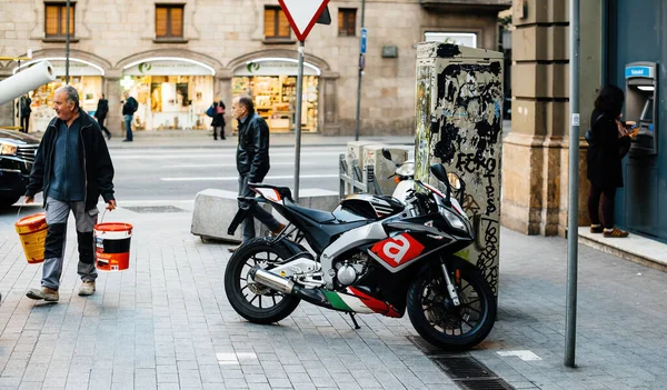 Barcelona calle con pintor llevando dos cubos de pintura en las manos caminando cerca de nuevo lujo Aprilia — Foto de Stock