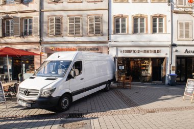 Beyaz Mercedes-Benz Sprinter minibüsü şehrin merkezindeki Le Comptoir de Mathilde mağazasının önünde mal indiriyor.