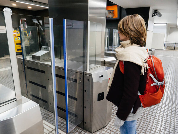Side view of woman preparing to enter metro underground station in front of automatic nfc activated ticket