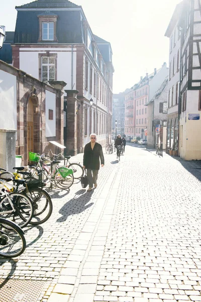 Temprano en la mañana en Estrasburgo con pocas personas en la calle hombre mayor caminando cerca de bicicletas estacionadas — Foto de Stock
