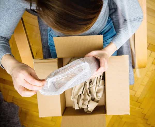 Vista aérea de la mujer curiosa unboxing en la sala de estar nueva entrega de productos pedidos de comercio electrónico a través de interne — Foto de Stock