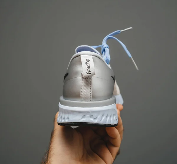 POV male hand holding isolated on gray background new Nike Odyssey React running shoes — стоковое фото