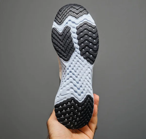 POV mano maschile tenuta isolata su sfondo grigio nuova scarpa da corsa Nike con logo Swoosh — Foto Stock