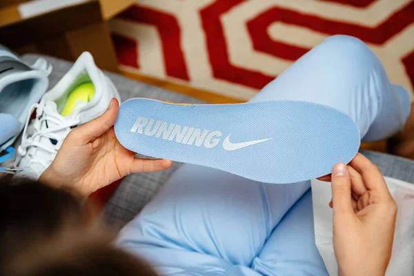 Felülnézetben nő kéz gazdaság új futó Nike cipő talp kék színű — Stock Fotó