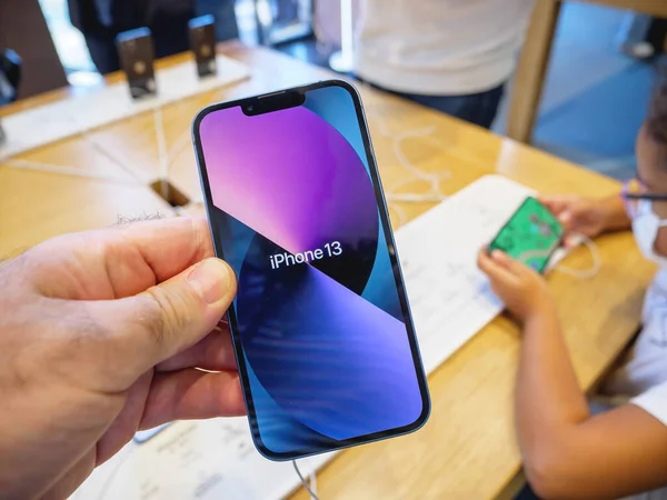 Homme tenant un nouvel iPhone 13 à l'Apple Store avec son fond d'écran coloré — Photo