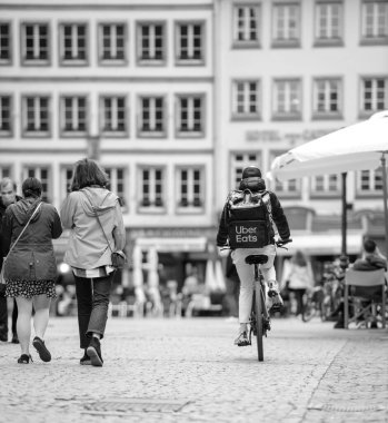 Sokak sahnesi - Uber Eats uygulaması işaretli motorcunun kendi kendine yeten işçisinin dikiz görüntüsü