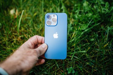 Apple Bilgisayarları iPhone 13 profosyonel üç arka kamerası ve yeşil bahçe çimen arka planında lidar sensörü çevre dostu