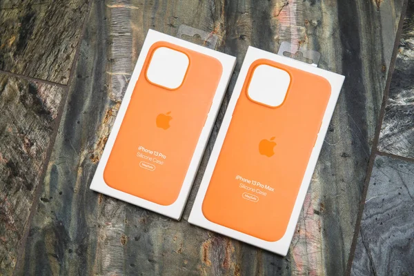 Dois computadores Apple Capas laranja de silicone para o mais recente iPhone 13 Pro telefone smartphone isolado no fundo de pedra — Fotografia de Stock