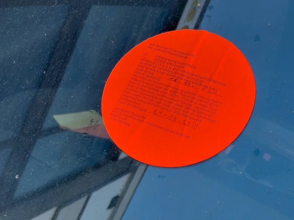 Czerwona naklejka na przedniej szybie samochodu informująca właściciela, że samochód zostanie podniesiony z powodu niezapłaconych mandatów za parkowanie na ulicy — Zdjęcie stockowe