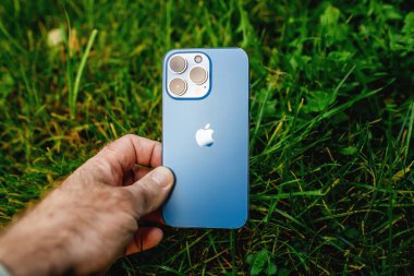 Apple Bilgisayarları iPhone 13 profosyonel üç arka kamerası ve yeşil bahçe çimen arka planında lidar sensörü çevre dostu
