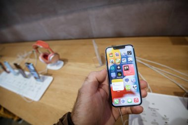 Apple Store 'da yeni iPhone 13' ü elinde tutan erkek el. Tüm uygulamalar ana ekranda.