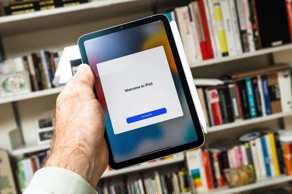 Livros de fundo mão masculina segurando novo ipad com Bem-vindo começar mensagem botão na nova sexta geração Apple Computadores iPad Mini — Fotografia de Stock