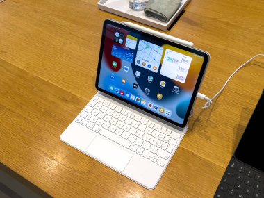 Yeni Apple Bilgisayarları iPad iPad. Yan tarafında kalem olan. Apple Store 'daki ahşap bankta.