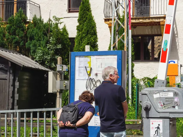 Rückansicht eines älteren Ehepaares, das auf der öffentlichen Touristenkarte seine Lage in Chamonix liest — Stockfoto