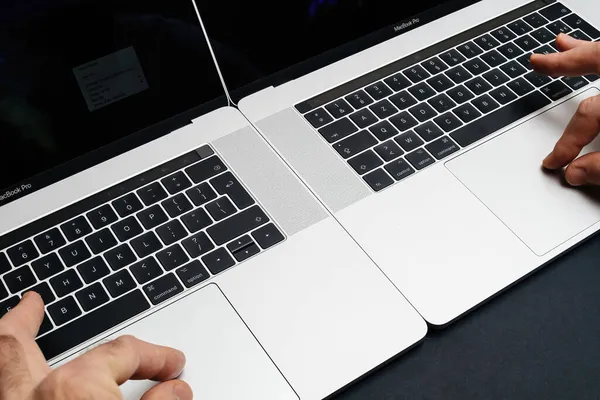 Mão masculina operando dois laptops simultaneamente profissional Apple MacBook Pro 16 — Fotografia de Stock