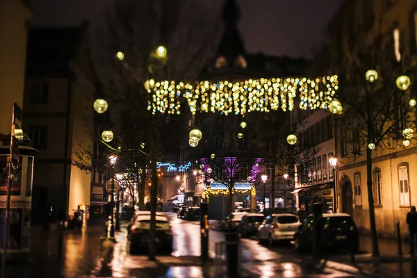 Rozostřená prázdná ulice s vánoční výzdobou nad ulicí a siluetami aut zaparkované - sklopný posun perspektivy ovládací čočky — Stock fotografie