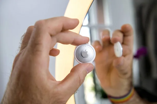 Hombre mano hoding nuevo Apple Computers AirTag dispositivo de seguimiento reflejado en el espejo —  Fotos de Stock