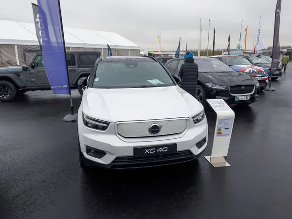 Donna che cammina con bambino nel passeggino ammirando la nuova auto elettrica di Volvo XC 40 — Foto Stock