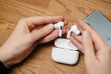 Yeni AirPods Pro kablosuz kulaklıklı kulaklığı açtıktan sonra elinde tutan kadın.