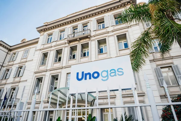 Önünde palmiye ağacı olan büyük binanın ön cephesinde Unogas tabelası — Stok fotoğraf