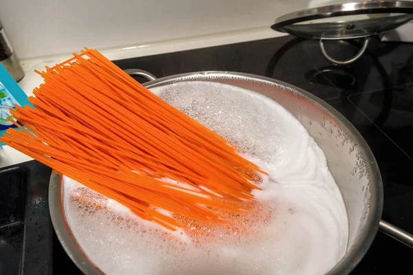 Grande casserole bouillante pâtes rouges orange sur table à induction — Photo