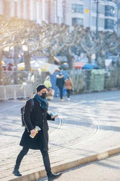 Hombre adulto soltero caminando sosteniendo la calle paquete de alimentos en el centro de la ciudad Place Broglie con máscaras respiratorias quirúrgicas — Foto de Stock