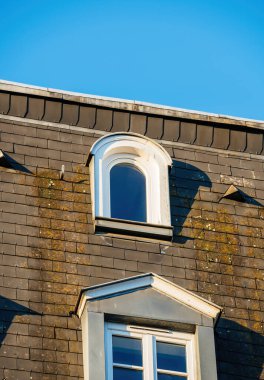 Arka planda açık mavi gökyüzü olan Mansarde penceresi