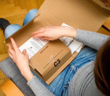Overhead view of curious woman unboxing in the living room new Amazon Prime