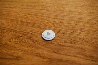 Ahşap zemindeki AirTag 'in üzerinde plastik film koruması