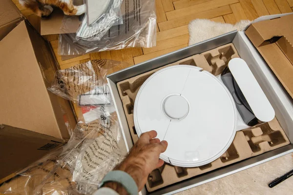 Hand unpacking new robotic vacuum cleaner during the unboxing process — ストック写真