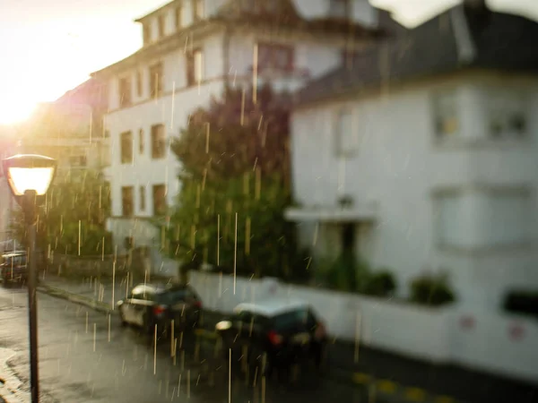 Rainy weather with drops of water falling form sky on the empty street with few cars — Stok fotoğraf