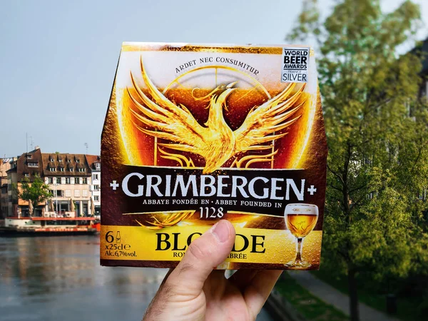 Male hand holding package with Grimbergen new Blonde zero alcohol beer — Stockfoto