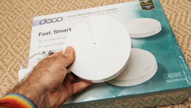 POV male hand holding new Deco Tp-Link mesh internet smart home wifi system after unboxing