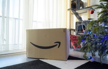 Amazon Prime logotype on cardboard parcel box next to Christmas tree
