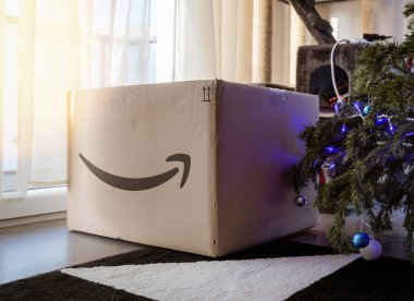 Amazon Prime logotype on cardboard parcel box next to Christmas tree in house