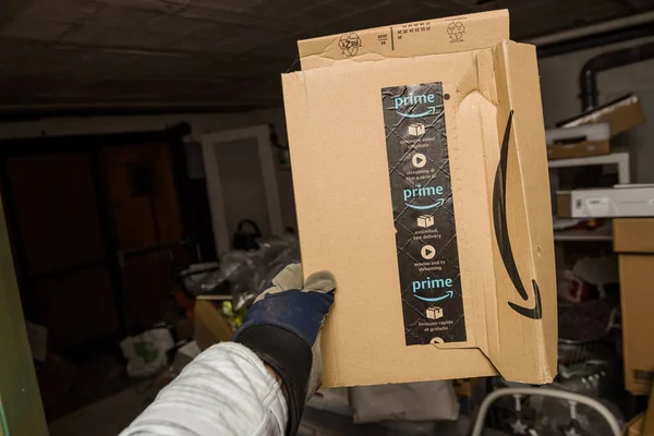 Male hand in protection glove holding slightly damaged in warehouse Amazon Cardboard box — Fotografia de Stock