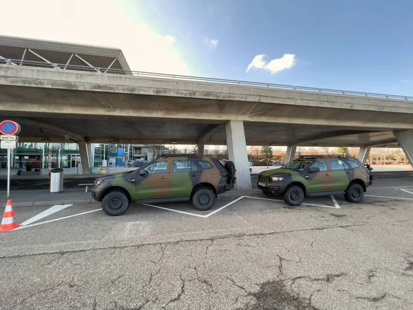 Two military SUV colored in green special army color parked in front of Civil Airport of EuroAirport Basel-Mulhouse-Freiburg — Stockfoto