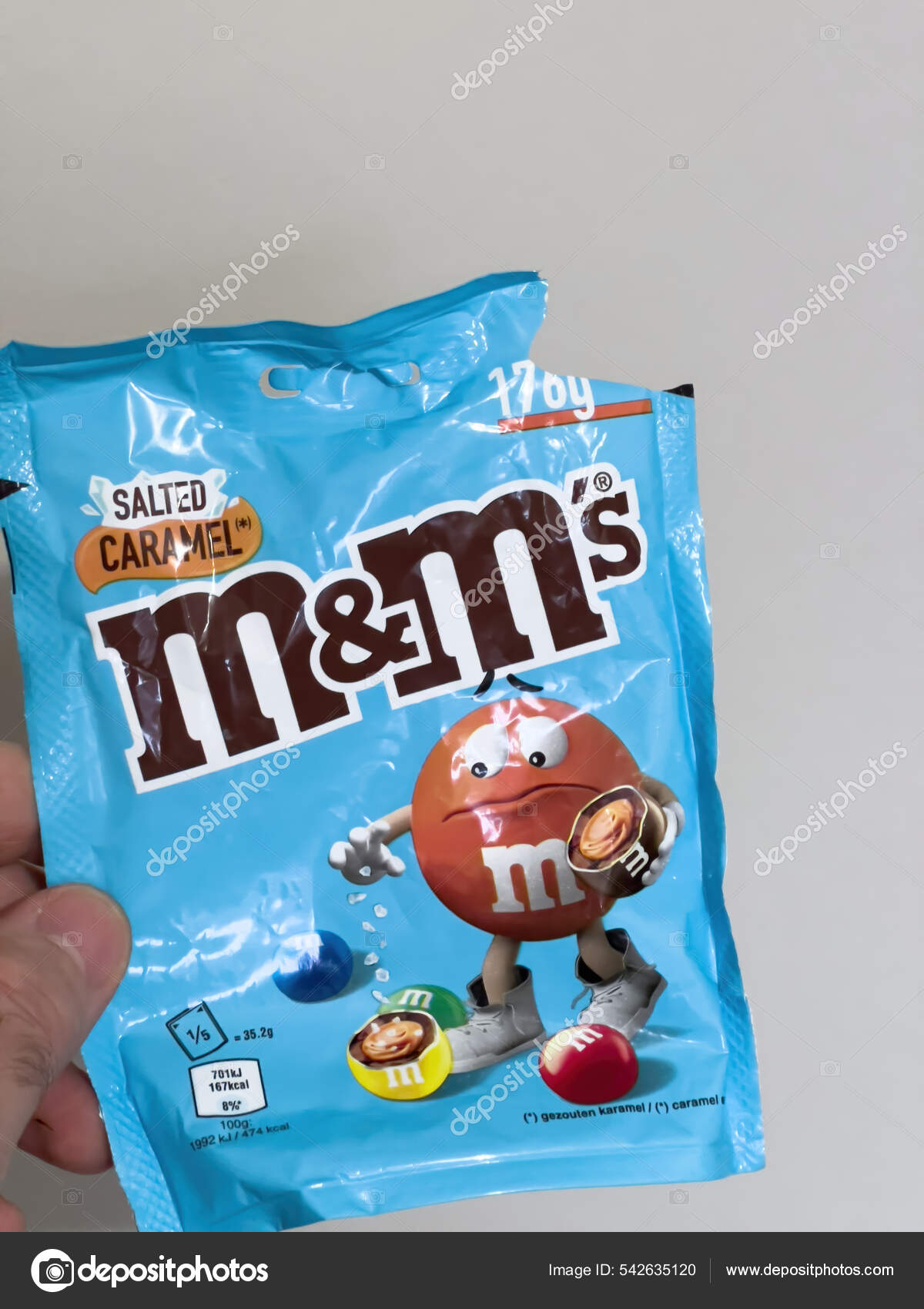 POV male hand holding plastic package with M and Ms salted caramel