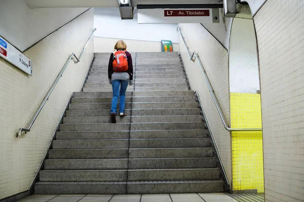 Visão traseira de uma jovem solteira com mochila vermelha andando na estação de metrô — Fotografia de Stock