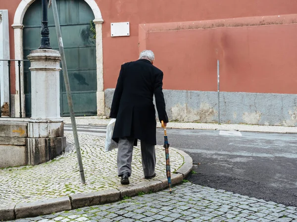 Single senior man with cane walking on the cobblestone trottoir in central Lisbon — Stock Photo, Image