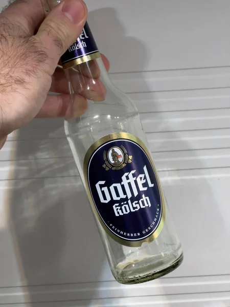 POV męska ręka trzymając emty butelki z Gaffel Kolsch niemieckie piwo — Zdjęcie stockowe