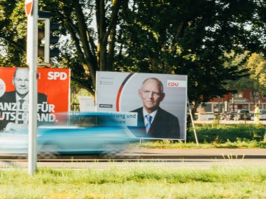 Olaf Scholz ve CDU Wolfgang Schaeuble ile SPD şansölye adaylarının bulunduğu büyük seçim afişlerinin yanından geçen bir araba görülüyor..