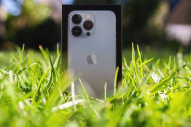 iPhone Apple Bilgisayarları Sienna Blue cep telefonu aygıtını yeşil çimlerde kapatır