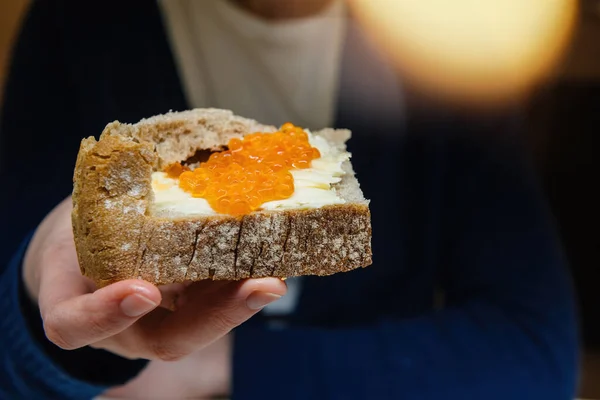 Donna che mostra alla macchina fotografica mangiare deliciosu Caviale rosso sul pane con burro — Foto Stock