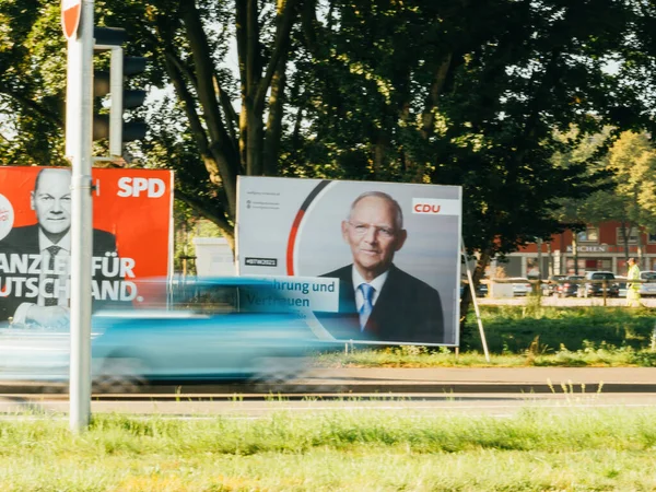 Un coche conduce más allá de grandes carteles electorales con los candidatos canciller del SPD con Olaf Scholz y CDU Wolfgang Schaeuble. — Foto de Stock