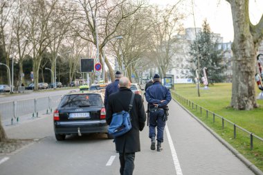 Polis memurlarının Avrupa Konseyi binasının yakınındaki bölgeyi gözetlediği şehir merkezinde yürüyen insanların dikiz görüşü