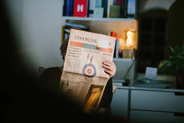 Mujer leyendo el periódico británico Financial Times con el titular de portada La UE prepara opciones de gas si la crisis de Ucrania golpea los suministros —  Fotos de Stock