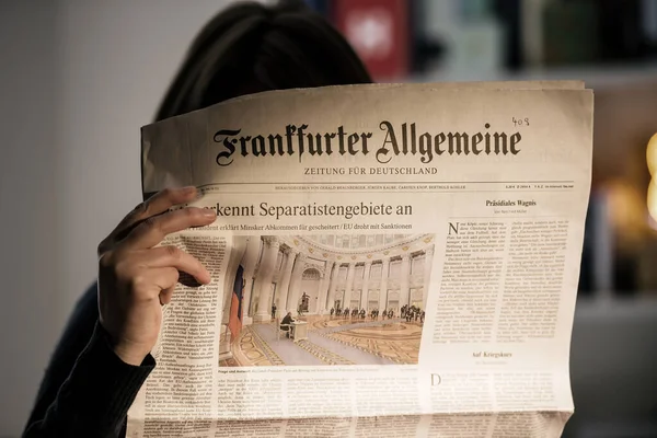 Mujer leyendo lte en la noche último periódico Frankfurter Allgemeine —  Fotos de Stock